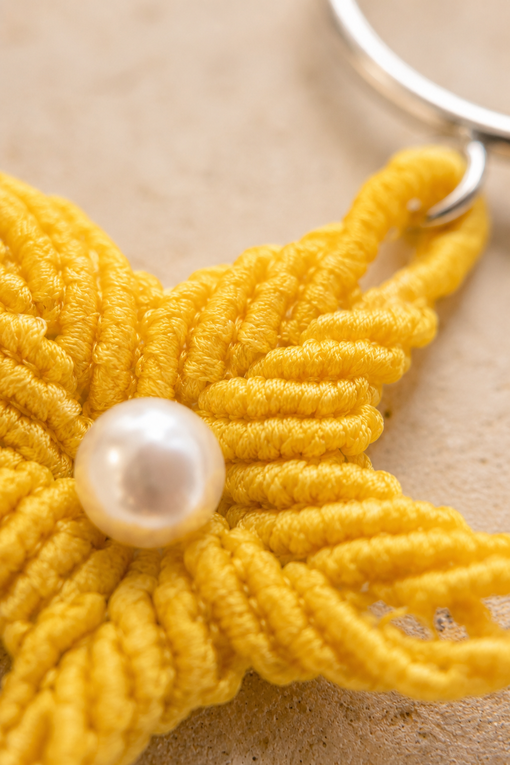 Gros plan sur les nœuds du micro-macramé et la perle de nacre au centre de l'étoile de mer